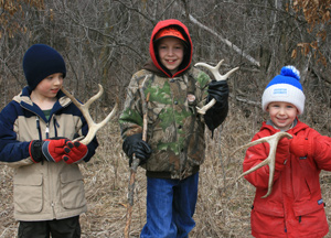 3 Children in a field holding deer antler sheds they found