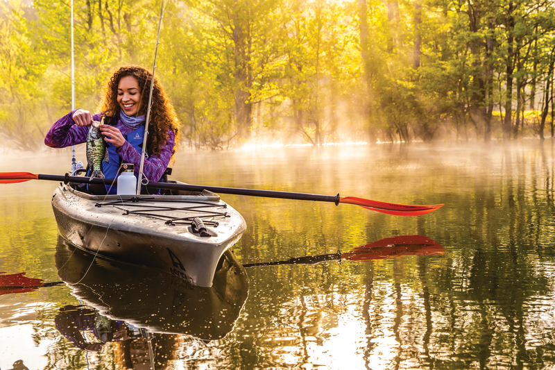 Woman fishing from Ascend kayak holding crappie