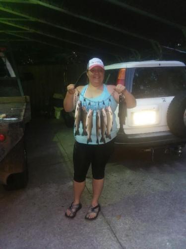 Lady angler in a parking lot hold up a stringer of trout