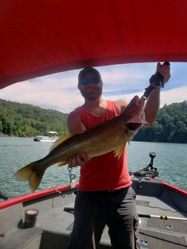 Man on a boat holding his large walleye up with a fish grip