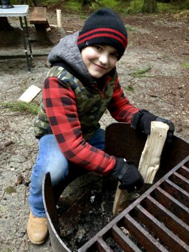 Young camper is building a camp fire
