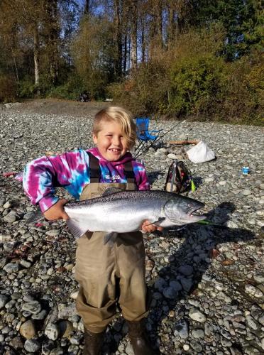Young boy holding up his salmon catch