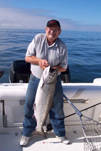 Angler standing in a boat, holding his salmon catch