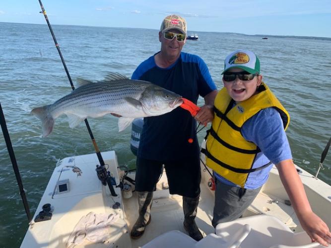 Family fishng striped bass is proud of this nice catch