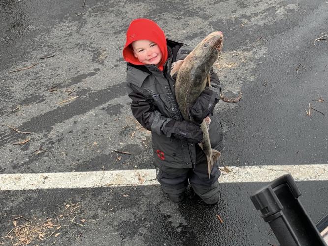Young boy hold a fish that is almost the boy's size