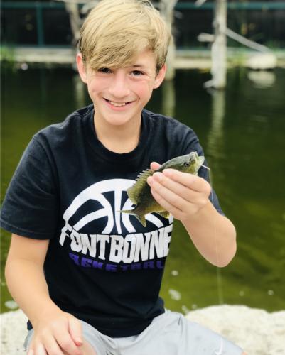 Boy angler hold up a small perch at Bass Pros gone fishing event