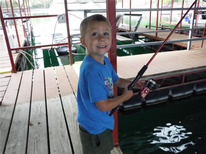 Young boy fishing from a boat dock