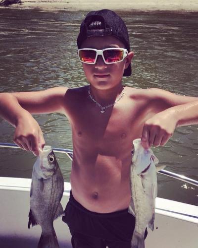 Two stripe bass held by a young angler