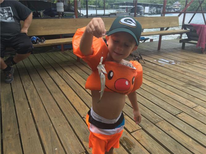 Young girl holding up a small fish