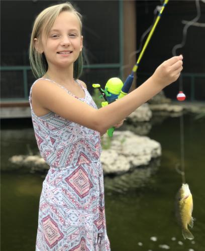 Young girl hold up a fish she caught at Bass Pros gone fishing event