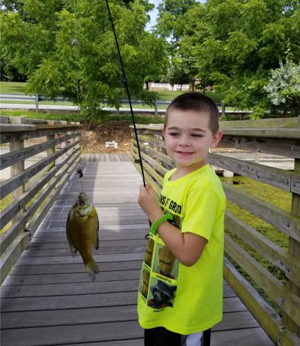 Young Hayden holding the fishing rod with his catch