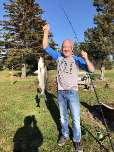 Angler standing on land holding up a nice stripe bass