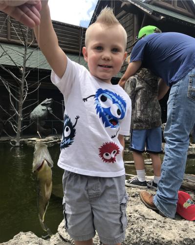 Young Jax holding up a fish at Bass Pro's kids fishing day