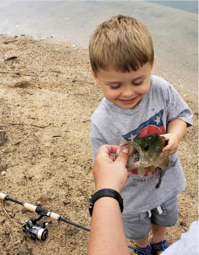 Small angler holding a bass looking into its mouth