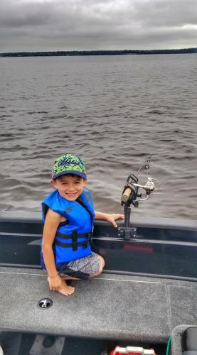 Young boy maning a trolling rig on a boat
