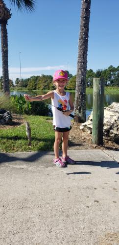 Little girl in pink bass pro hat holding up a fish