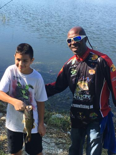 Boy angler with bass standing with a pro angler