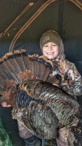 Boy turkey hunting with large gobbler