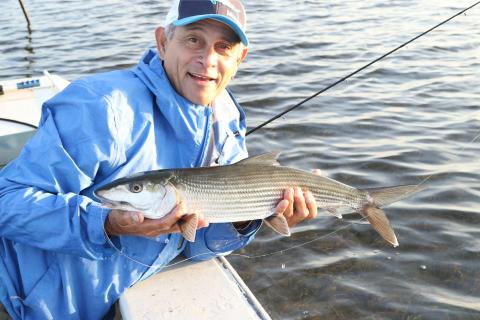 Angler on a boat holding a bonefish. photo by David A. Brown