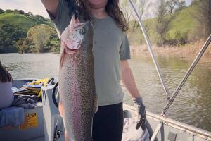 Young Gwendolyn standing in a boatholding a large salmon fish 