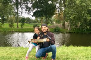 Father - daughter holding up a young norther pike on a summer day near the waters edge