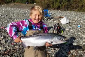 Young boy holding up his salmon catch