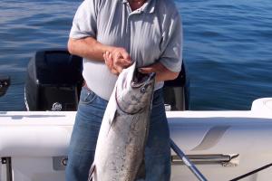 Angler standing in a boat, holding his salmon catch