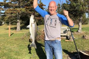 Angler standing on land holding up a nice stripe bass