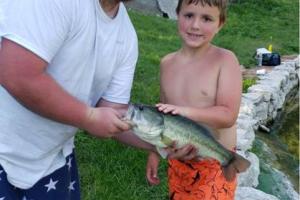 Young angler with his father holding up his fish