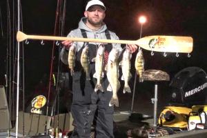 Walleye angler staning in a boat at night with six walleye catches