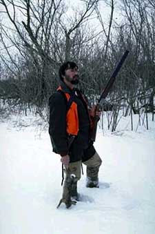 Rabbit hunting standing in the snow holding a rabbit