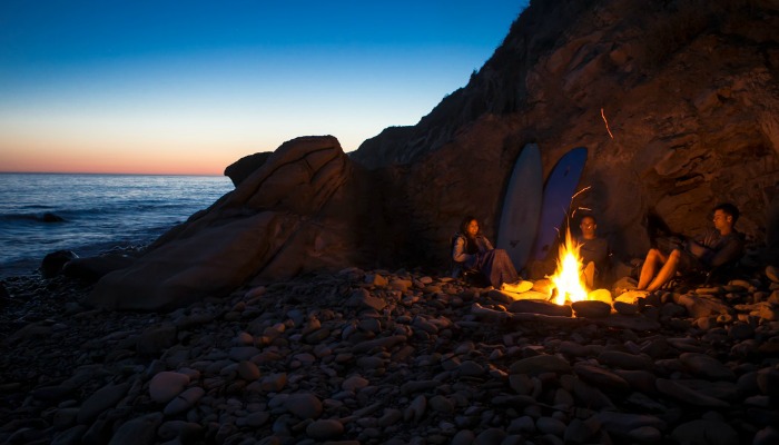 People camping on a beach by large boulders