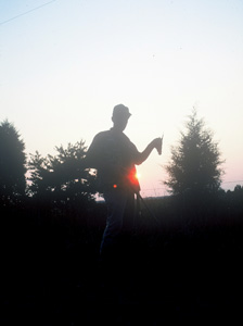 Man in dusk shadow holding shotgun