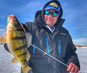 Jason Mitchell holding a perch while ice fishing