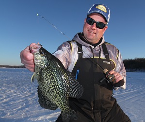 Jason Mitchell holding a large crappie on a frozen lake