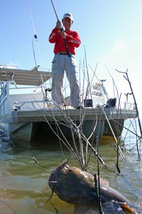 Angler on a boat reeling in a large catfish
