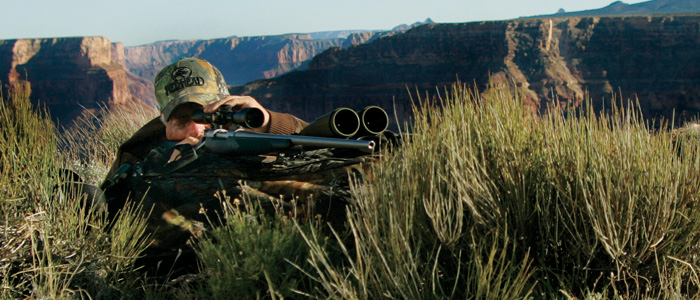 Hunter with his rifle looking through a rifle scope