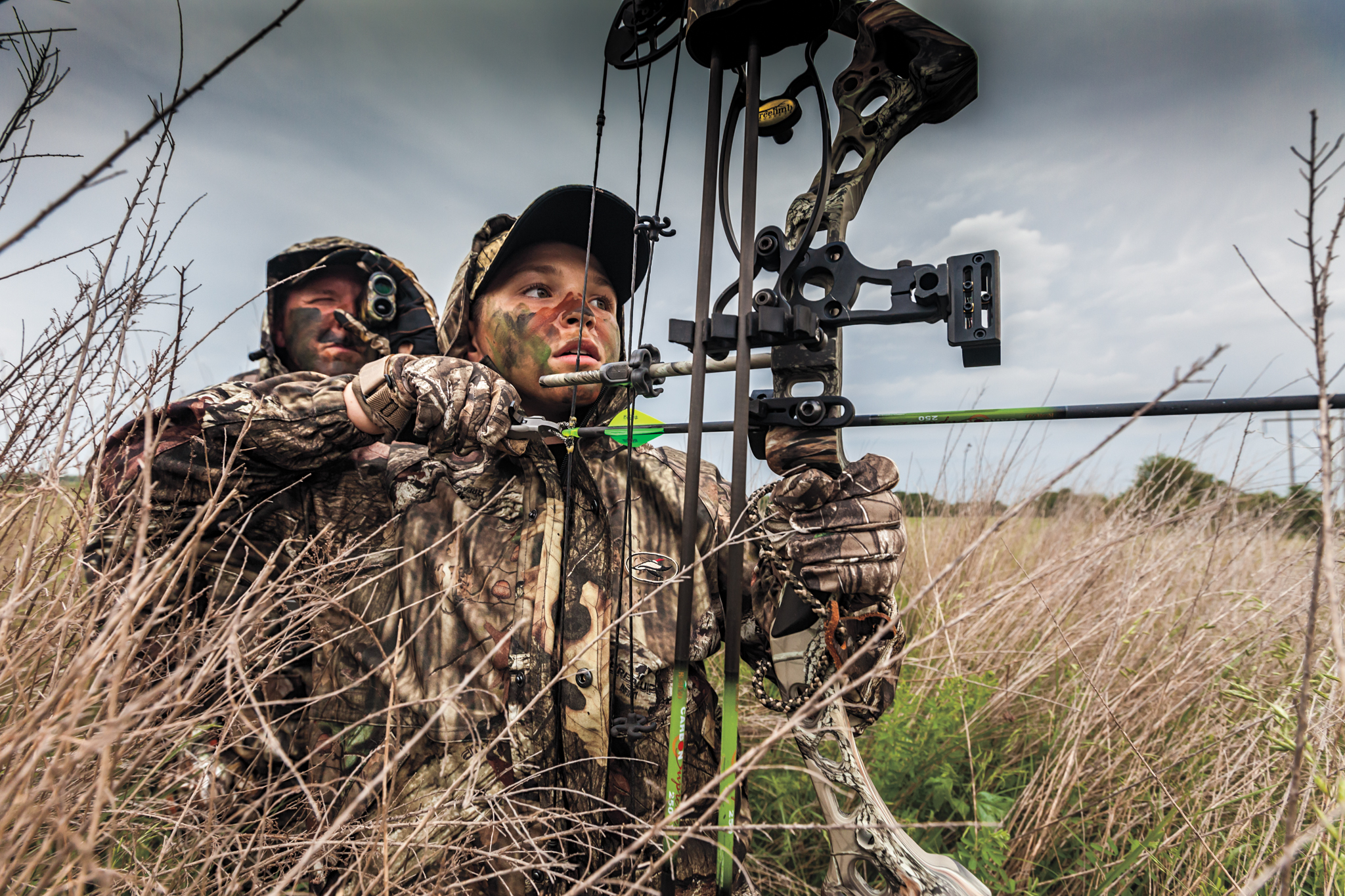 father and son on archery hunt in field