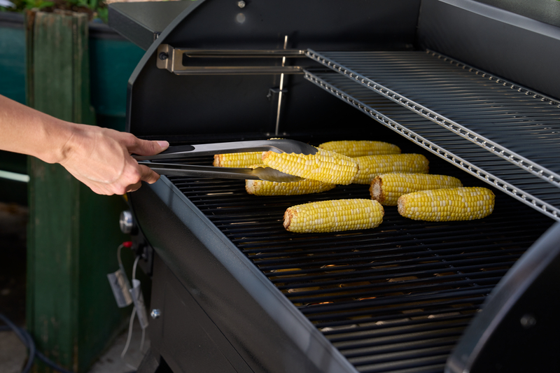 turning corn over on grill as it cooks