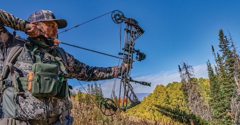 Hunter drawing his bow in Utah woods