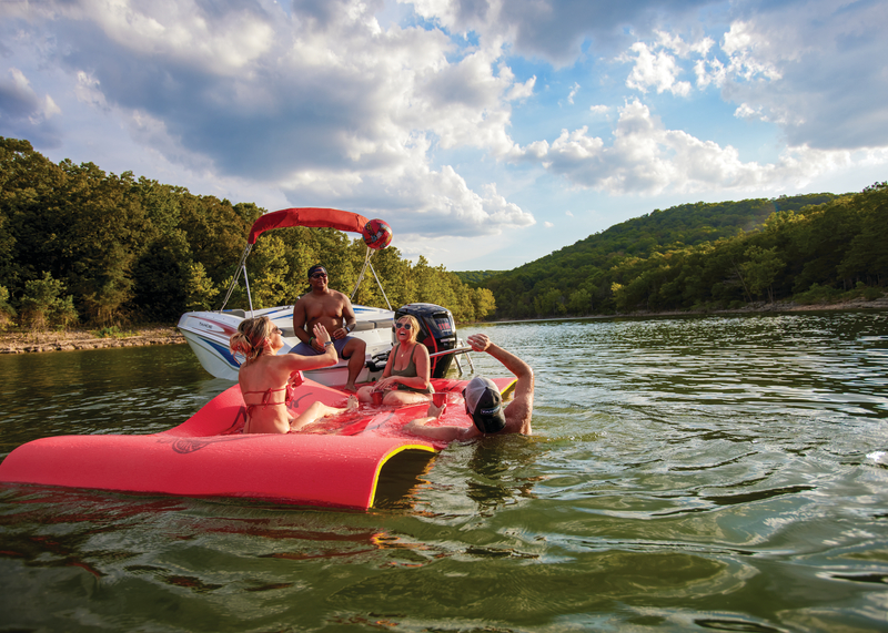 Group of swimmers serving up water ball from boat and float