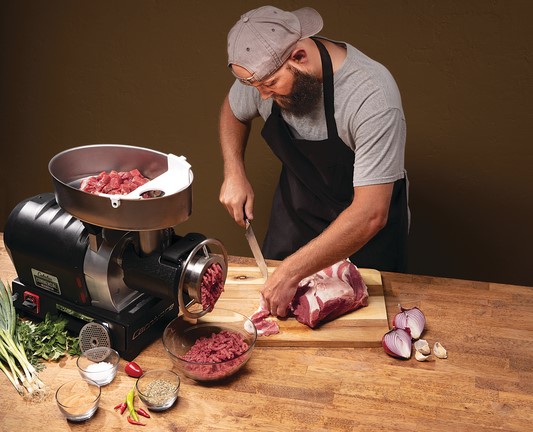 Man cutting meat and grinding meat using Cabela's Carnivore