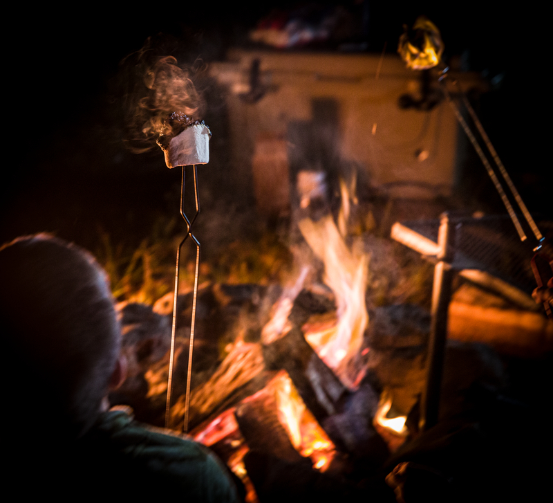 camper making smores over campfire