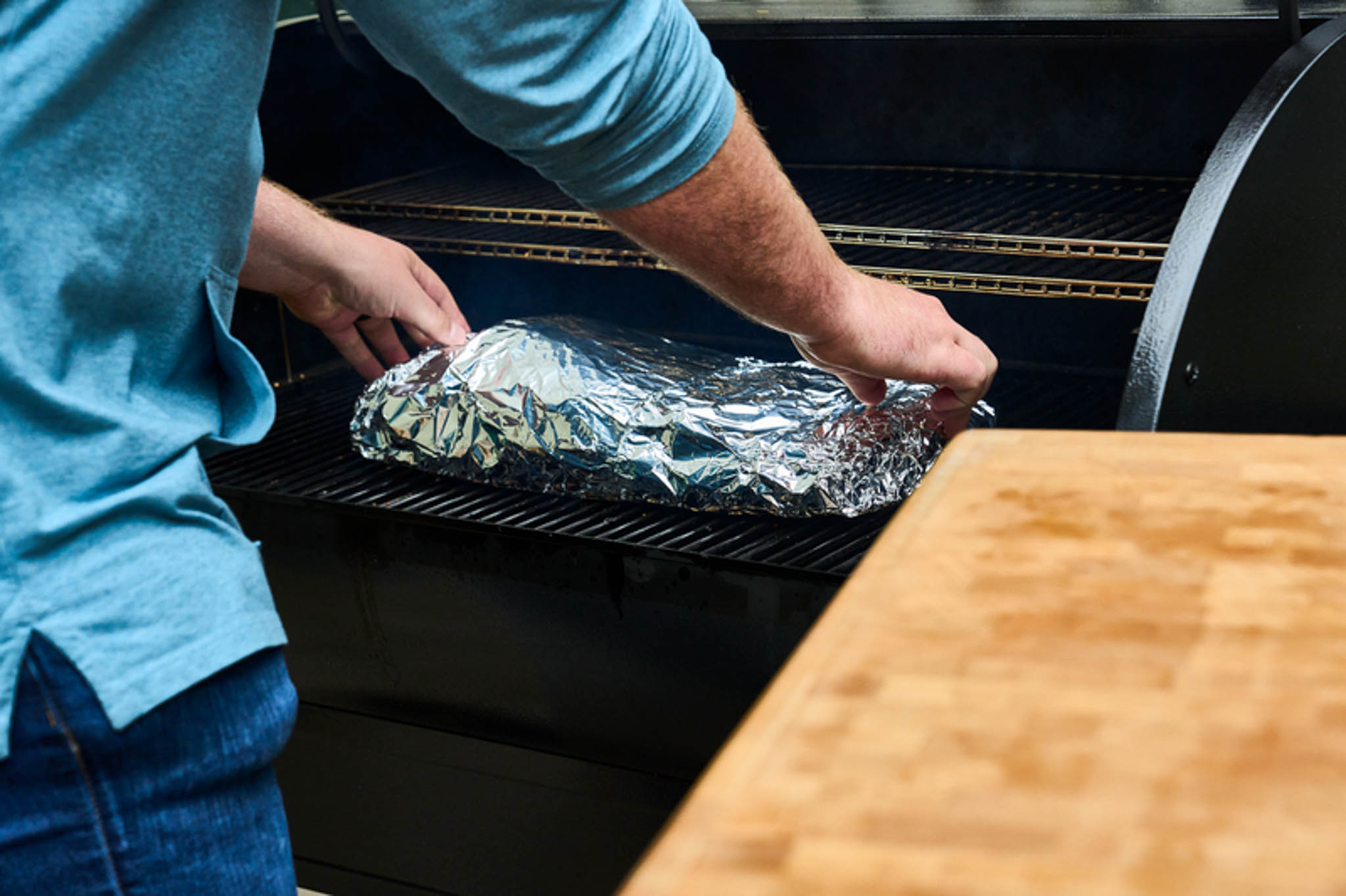 Placing foil-wrapped brisket on grill