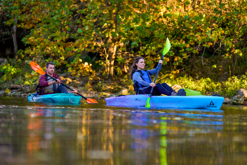 two kayakers paddling downstream in recreational kayaks