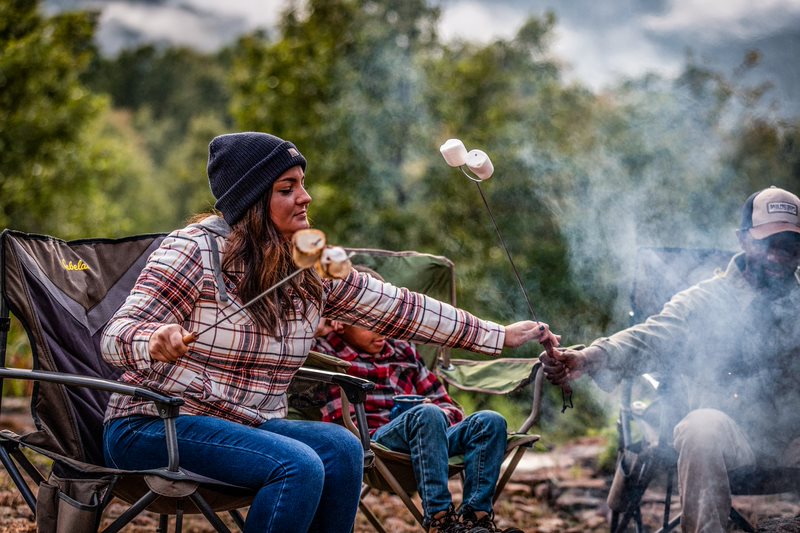 Family using their camp chairs around fire