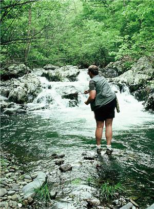 Fly fishing angler standing near a small water rapid fly casting