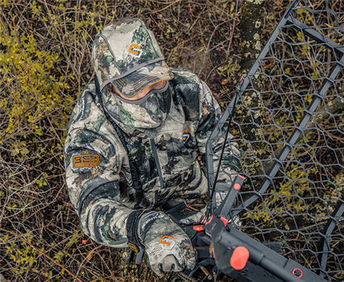 Deer hunter on the ground setting up a treestand wearing a Scent-Lok BE:1 Voyage Jacket