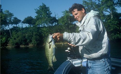 Angler holding a fat bass with fishing rod and reel