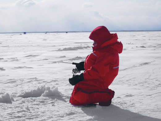 Angler kneeling on ice,  ice fishing